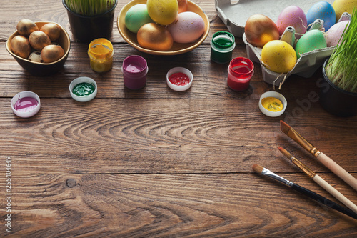 Colorful easter eggs and brushes on wooden table