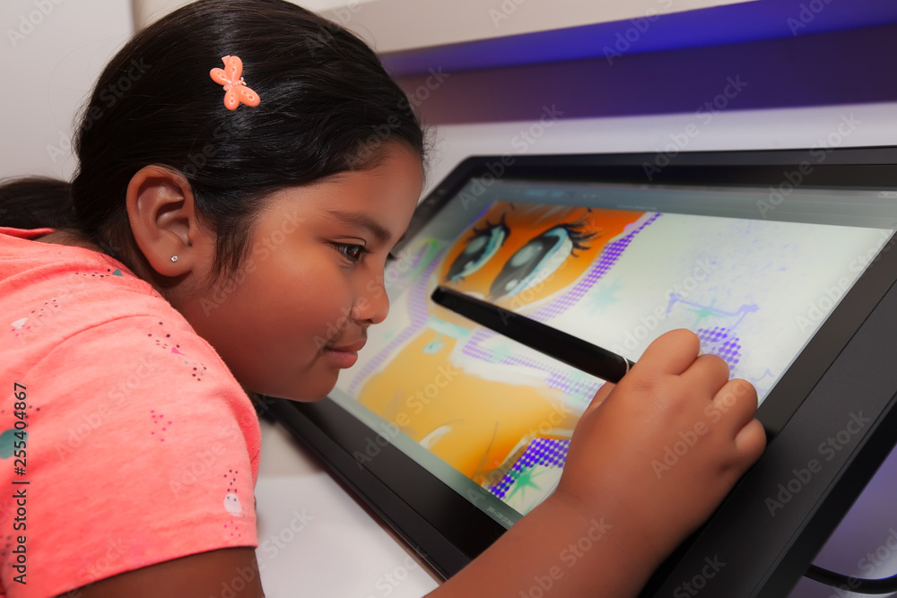 Young girl using a digital pen and drawing tablet to be creative and to make digital art in a