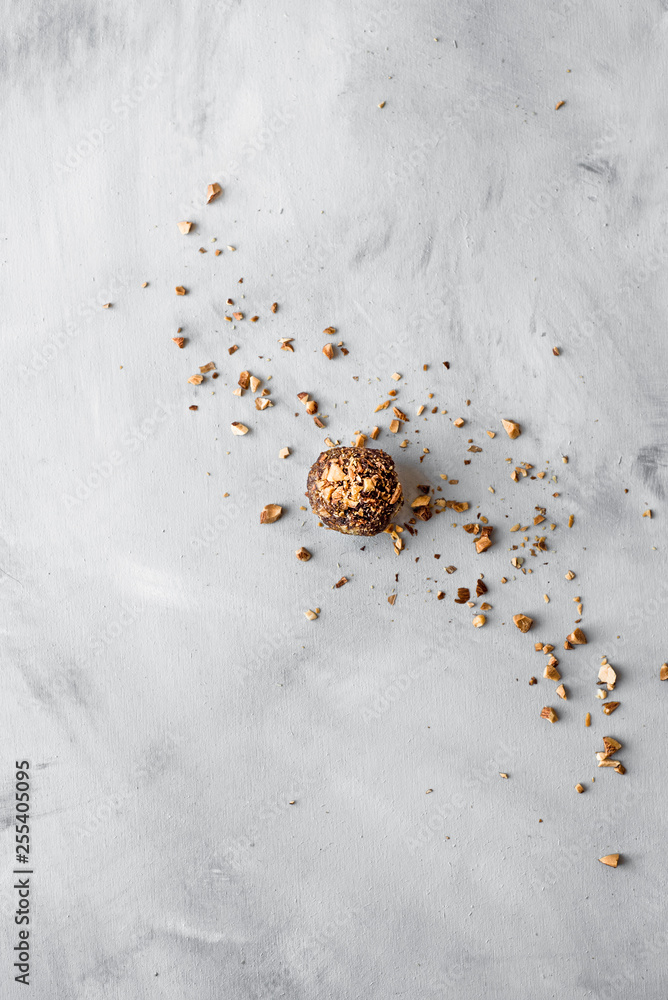 Raw healthy bliss ball with chopped nuts on a textured background with a copy space Raw healthy bliss ball with chopped nuts on a textured background with a copy space