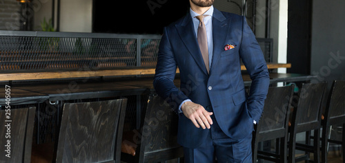 Man in expensive custom tailored suit standing an posing indoors