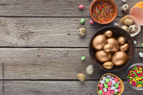 Golden eggs and candies on wooden background