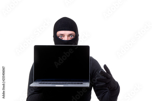 Thief man in black mask with laptop with blank screen in hands.