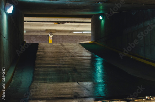 The long wet parking garage ramp in the glowing dim lights. 