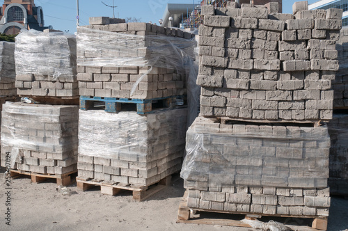outdoor warehouse with lot of pallets full of bricks pavement stones