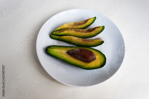 Avocado slices with salt and pepper on a plate, view from above. Candid.