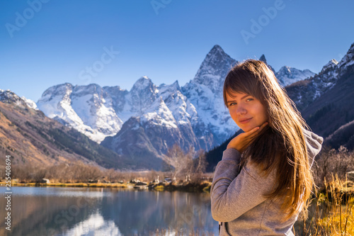 Beautiful young russian woman in front of autumn landscape with mountain lake Tumanly-kel, the Mist lake, located in Russia, near Dombay , in Caucasus mountains, Gonachkhir gorge
