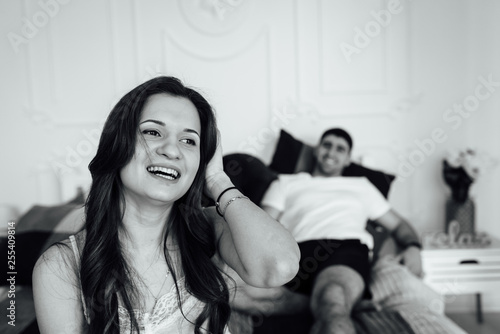 Laughing young people in pajamas playfully posing at sofa. Happy couple smiling in morning
