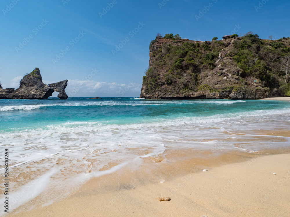 The Atuh beach, Nusa Penida island near Bali, Indonesia. Ocean waves, cliffs and a desert beach with tropical plants. October, 2018