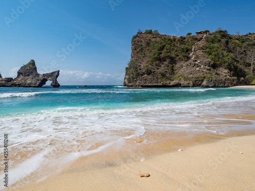 The Atuh beach, Nusa Penida island near Bali, Indonesia. Ocean waves, cliffs and a desert beach with tropical plants. October, 2018