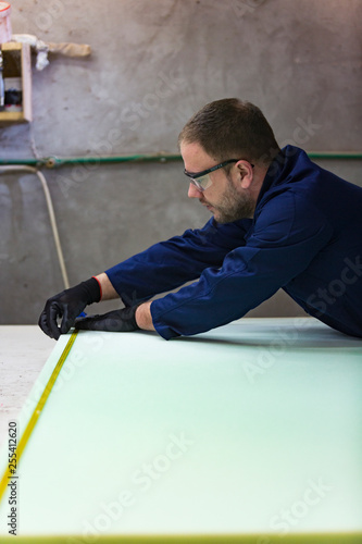 Young man in a furniture factory is measuring the foam for the sofa.