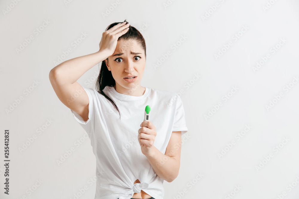 Young sad woman looking on pregnancy test at studio. Young sad woman looking on pregnancy test at studio.