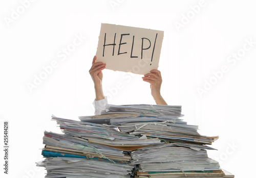 Person under a pile of papers with a hand holding a sign of help. Accounting. photo