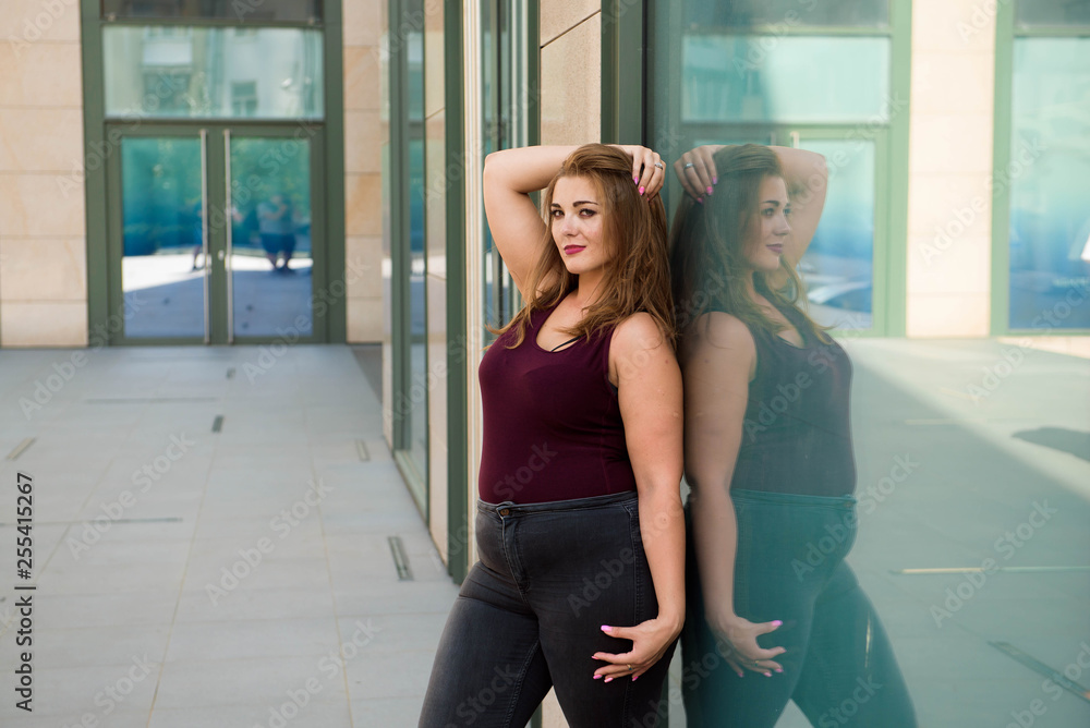 Obraz premium Pretty young woman walking on the city street. Casual fashion, plus size model. xxl women on nature.