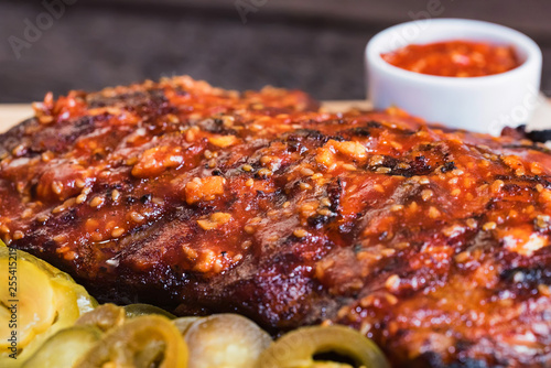 Close up roasted pork ribs with spices  jalapeno and ketchup on wooden board