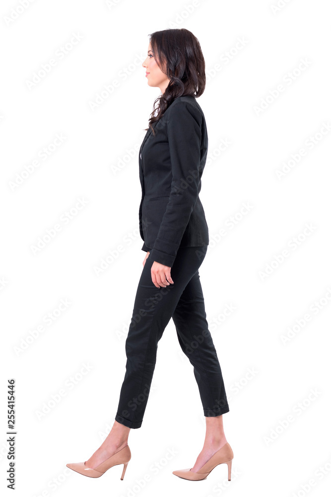 Side view of business woman in black suit smiling and walking with arms down. Full body isolated on white background. Side view of business woman in black suit smiling and walking with arms down. Full body isolated on white background.