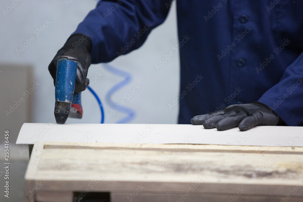 Closeup of a young man in a furniture factory who puts together one part of the sofa with a stapler Closeup of a young man in a furniture factory who puts together one part of the sofa with a stapler