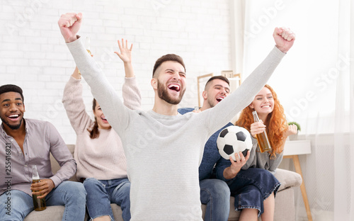 Happy football fans watching soccer on tv © Prostock-studio