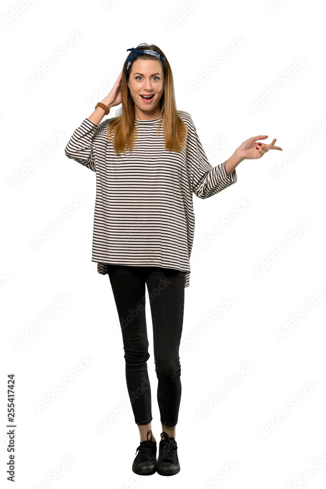 A full-length shot of a Young woman with headscarf surprised and pointing finger to the side over isolated white background A full-length shot of a Young woman with headscarf surprised and pointing finger to the side over isolated white background