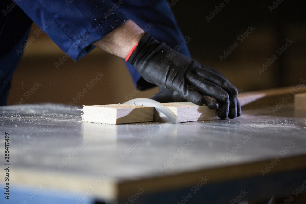 Close up of a young man in a furniture factory cutting the wooden pieces for the sofa