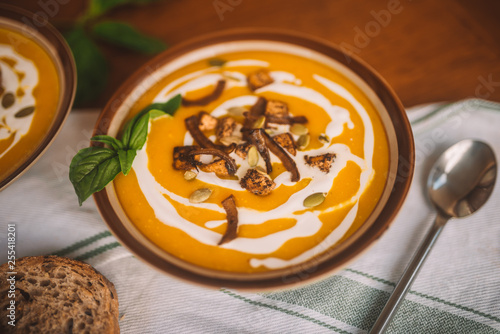  tasty autumn coconut pumpkin cream soup bowl with tofu, caramelized onion and seeds
