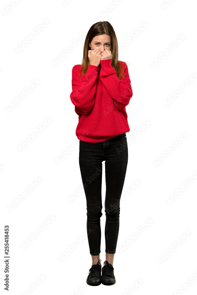 A full-length shot of a Young woman with red sweater nervous and scared putting hands to mouth over isolated white background A full-length shot of a Young woman with red sweater nervous and scared putting hands to mouth over isolated white background