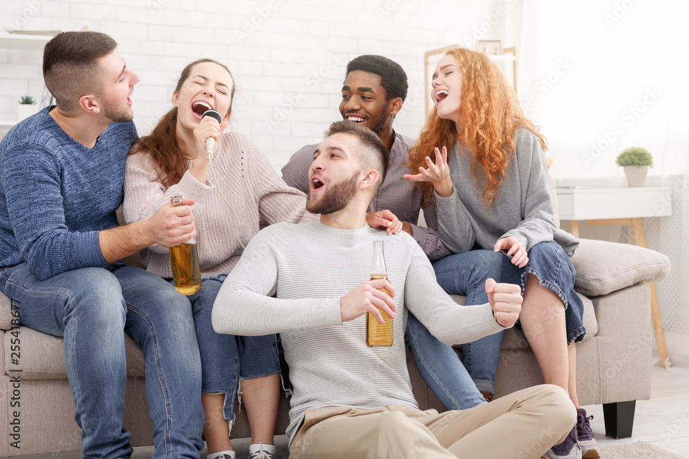 Group of friends playing karaoke and drinking beer
