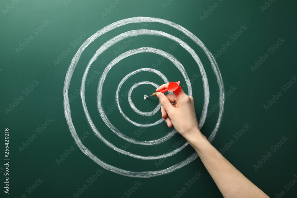 Φωτογραφία Woman with dart and chalk drawing of target  on green background, closeup
