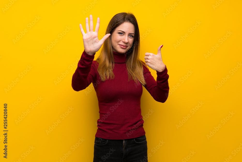 Woman with turtleneck over yellow wall counting six with fingers Woman with turtleneck over yellow wall counting six with fingers