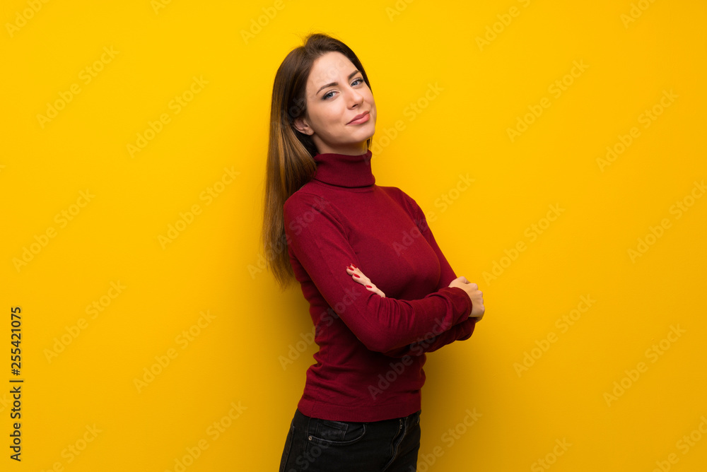Obraz premium Woman with turtleneck over yellow wall with arms crossed and looking forward