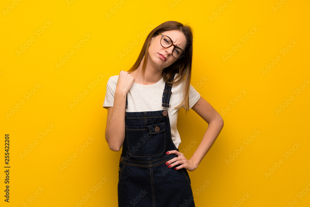 Woman over yellow wall with tired and sick expression Woman over yellow wall with tired and sick expression