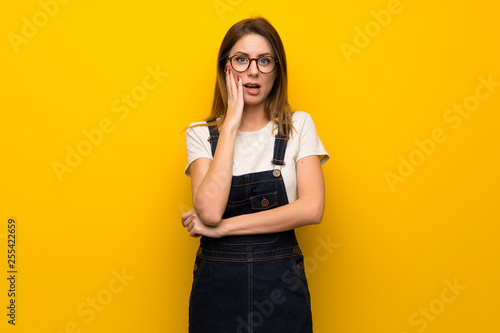 Woman over yellow wall surprised and shocked while looking right