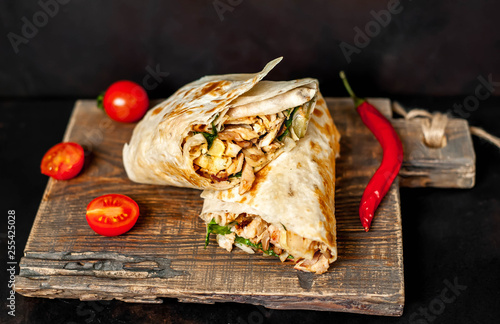 Burrito wraps with chicken and vegetables on a cutting board, against a background of concrete, Mexican shawarma