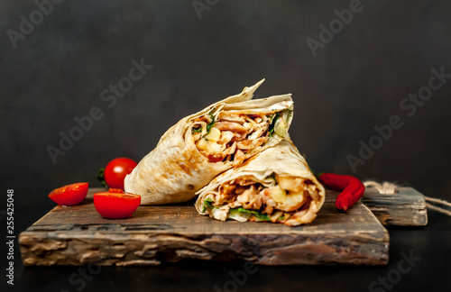 Burrito wraps with chicken and vegetables on a cutting board, against a background of concrete, Mexican shawarma photo