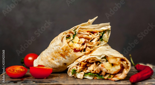 Burrito wraps with chicken and vegetables on a cutting board, against a background of concrete, Mexican shawarma
