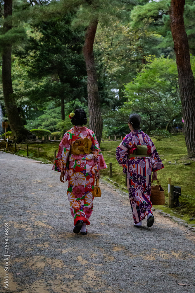 two Japanese women walk through park