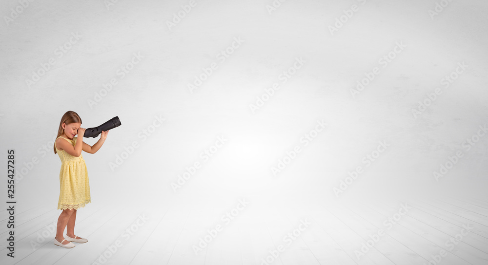 Obraz premium Cute little girl looking through spyglass to an empty space 