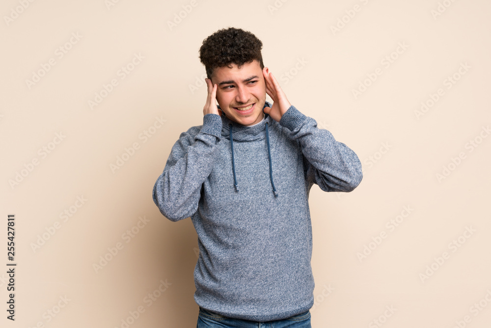 Young man over isolated wall frustrated and covering ears Young man over isolated wall frustrated and covering ears