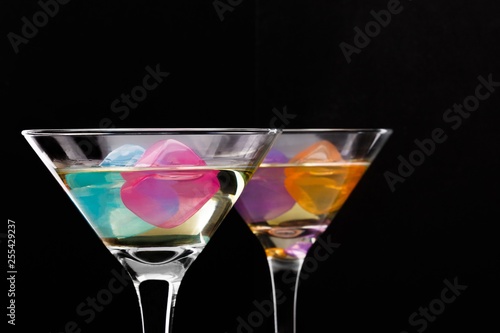 wine glasses with colored ice cubes on black background. Selective focus