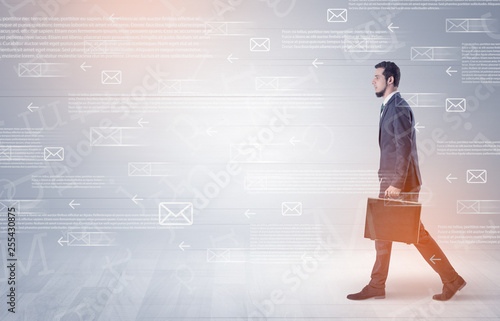 Handsome businessman walking in suit with briefcase on his hand and online communication concept around 