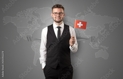 Fotografía Cheerful businessman standing in front of a map with flag on his hand