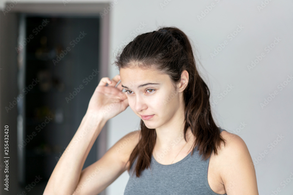 teen girl holds her hand over her head, emotion is puzzled and thoughtful teen girl holds her hand over her head, emotion is puzzled and thoughtful