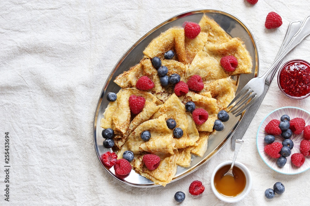 Crepes with fresh berries and raspberry marmalade. Thin pancakes with raspberry and blueberry. Overhead view Crepes with fresh berries and raspberry marmalade. Thin pancakes with raspberry and blueberry. Overhead view