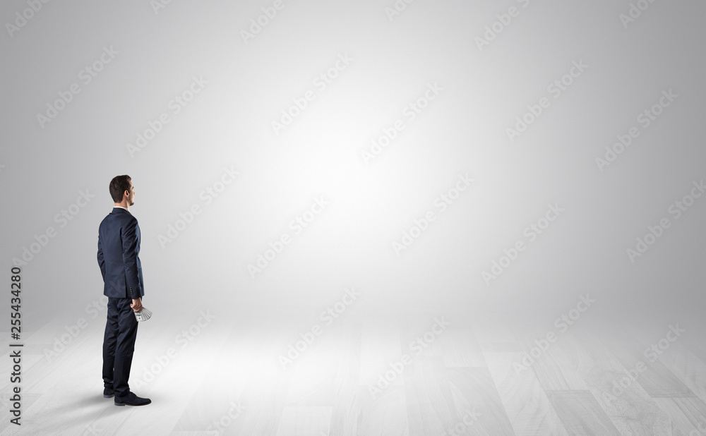 Man standing with his back in an empty room with object in his hand Man standing with his back in an empty room with object in his hand