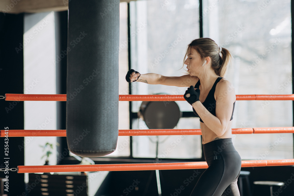 Beautiful Woman training punching bag in fitness studio fierce strength fit body