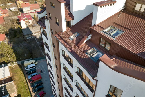 Aerial top view of new tall apartment building with annex room covered with metal siding and attic windows in quiet area.