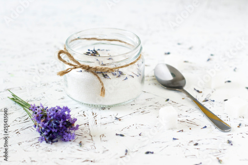 Glass jar with lavender sugar, fresh lavender on a light wooden background