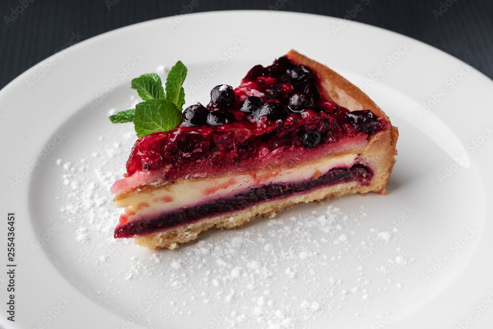 slice of cheesecake with berry jelly and mint on a white plate, close-up slice of cheesecake with berry jelly and mint on a white plate, close-up