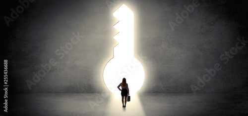 Woman standing alone in front of a big keyhole
