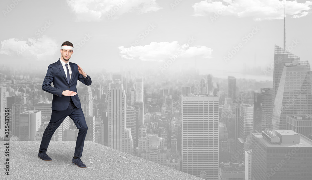 Young suited karate trainer doing karate tricks on the top of a metropolitan city
Young suited karate trainer doing karate tricks on the top of a metropolitan city