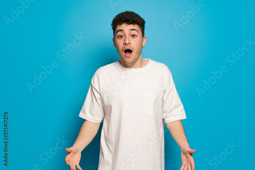 Young man over blue background with surprise and shocked facial expression